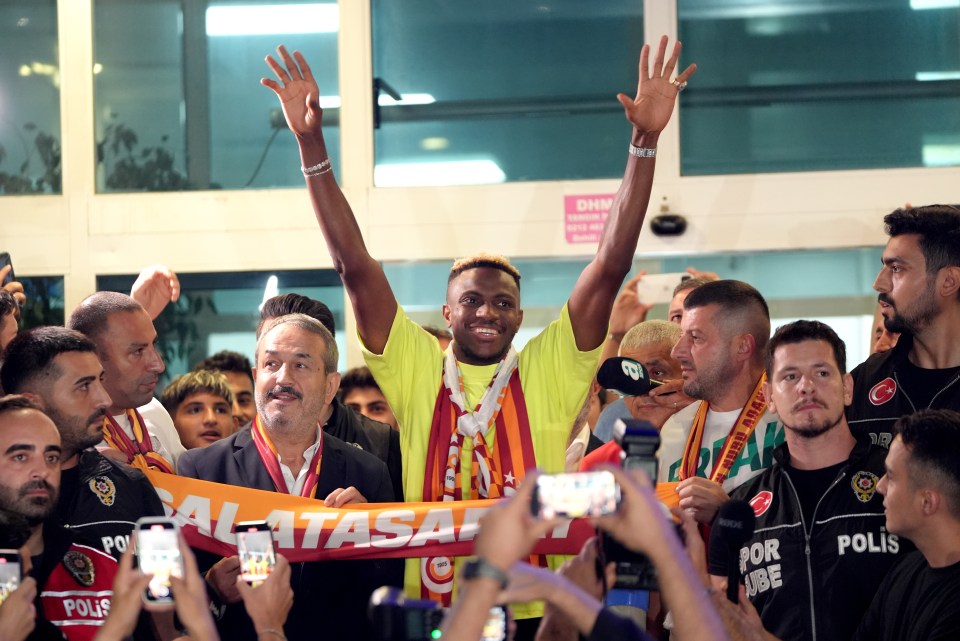 a man wearing a galatasaray scarf stands in a crowd of people