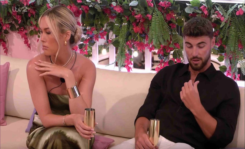 a man and a woman are sitting on a couch with flowers in the background