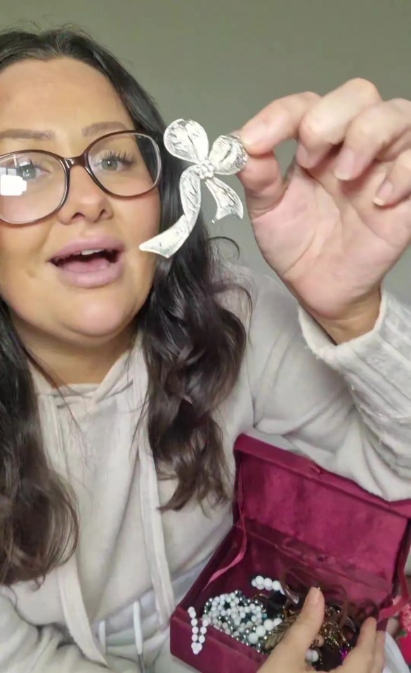 a woman wearing glasses holds a silver bow in her hand