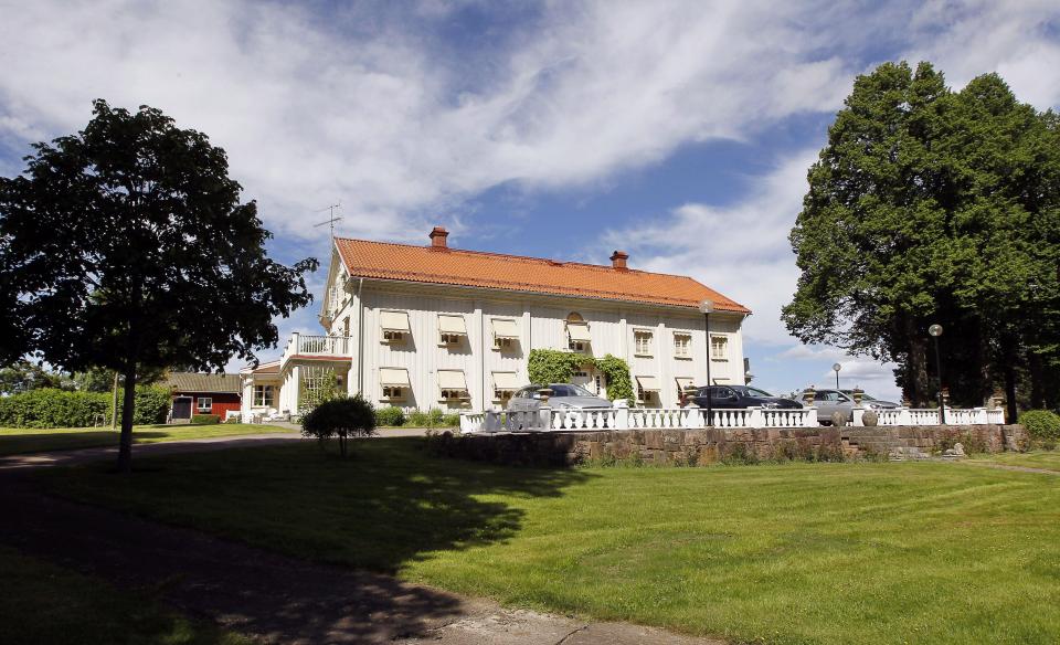 a large white house with a red roof is surrounded by trees