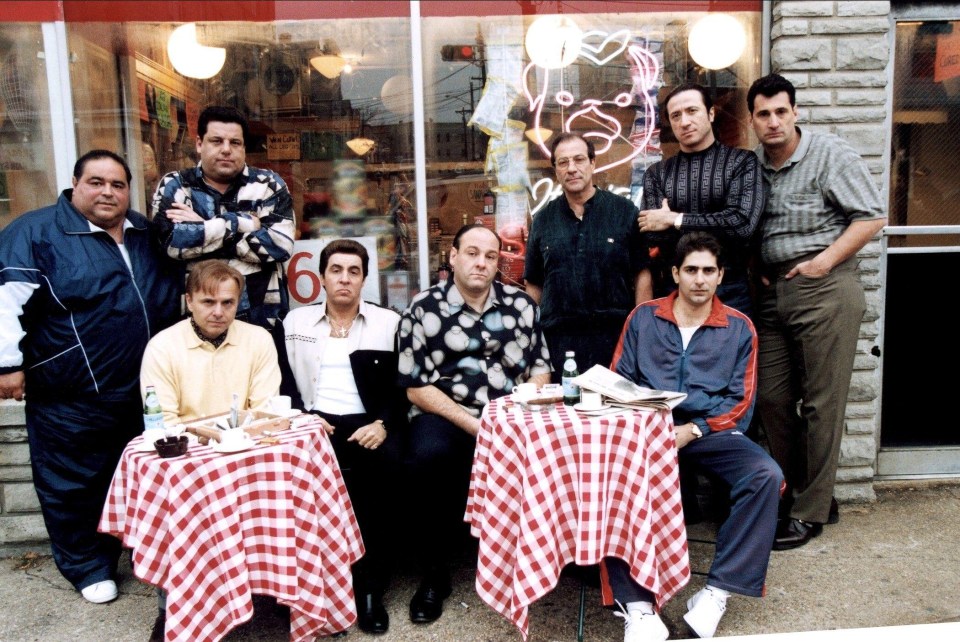 a group of men are posing for a picture in front of a store that has the number 6 on it