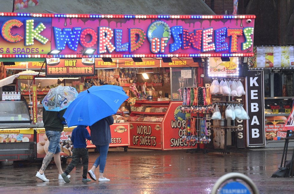 Brits shelter under umbrellas as heavy rain hits Blackpool today