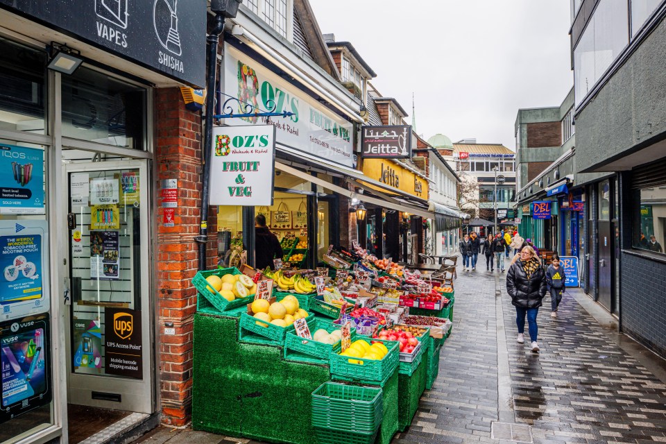 a woman walks past a boz 's fruit and veg store