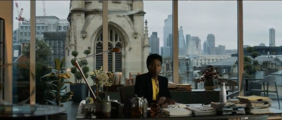 a woman sits at a desk with a view of the city