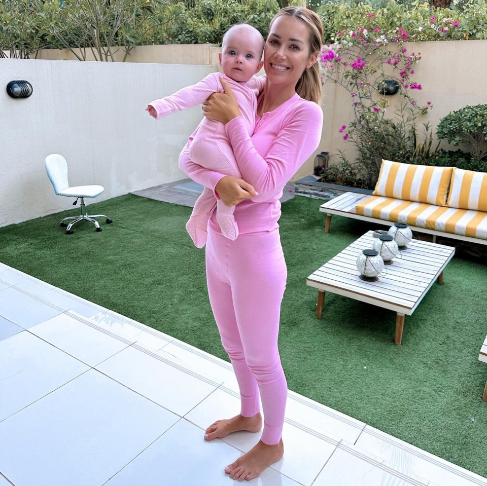 a woman in pink pajamas holds a baby in her arms