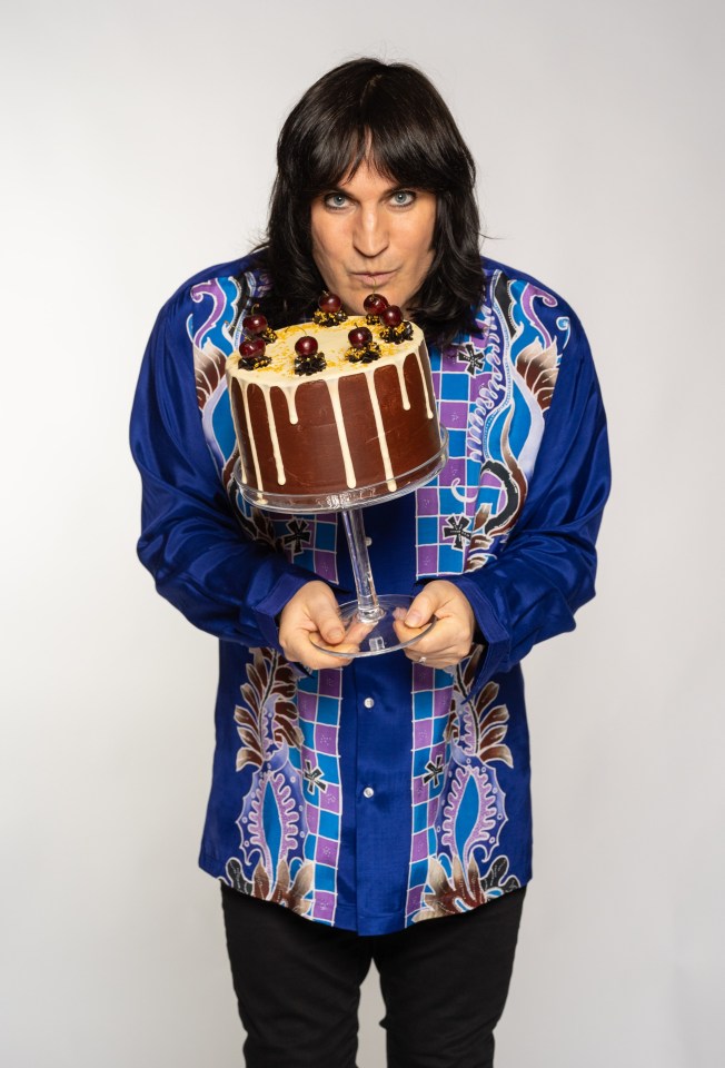 a man in a blue shirt is holding a cake