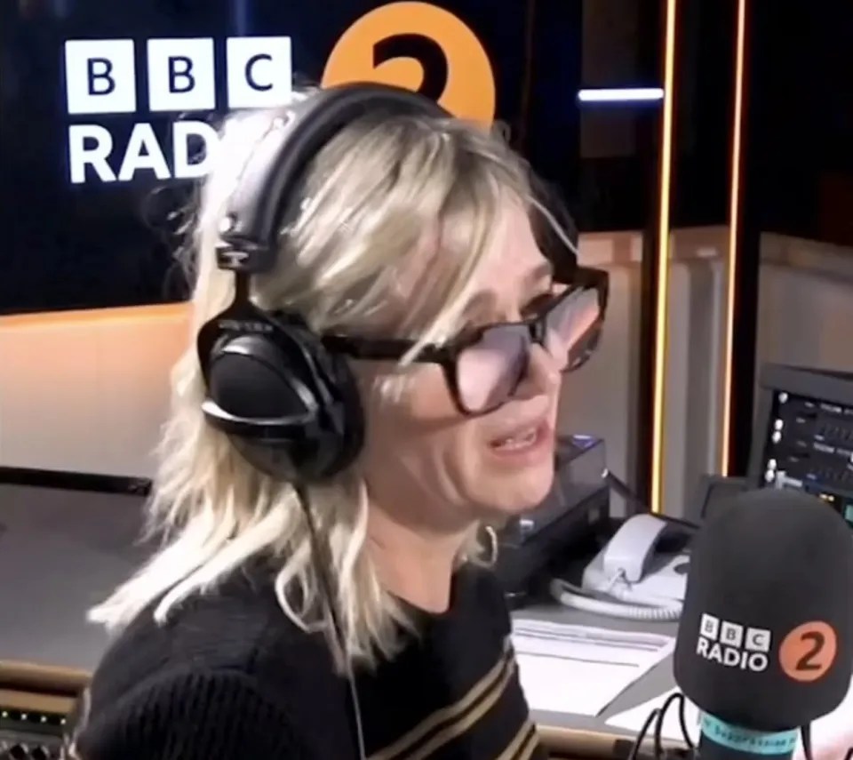 a woman wearing headphones and a bbc radio 2 microphone