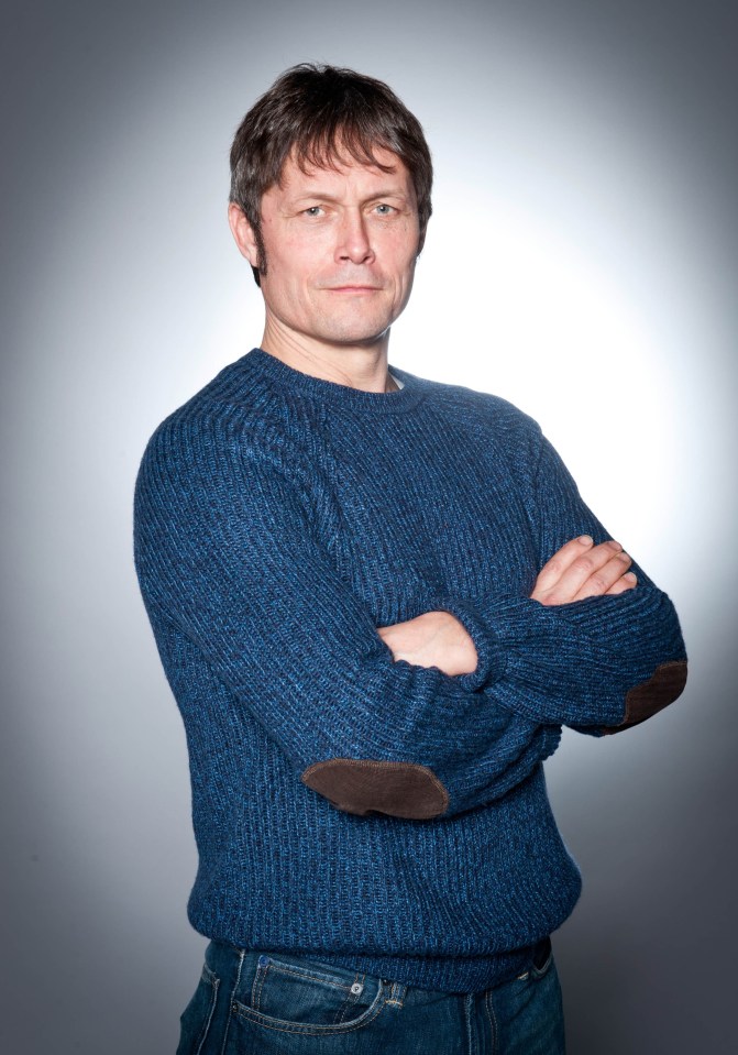 a man in a blue sweater has his arms crossed