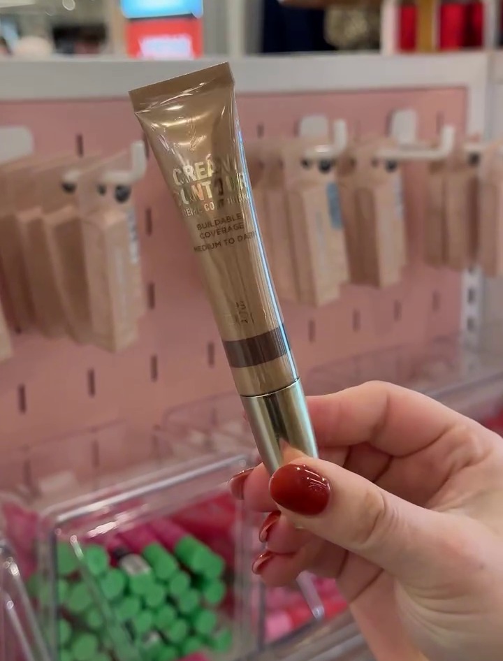 a woman is holding a tube of cream foundation in her hand