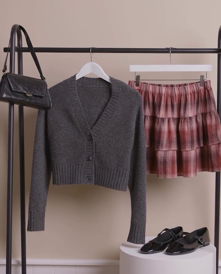 a sweater and a plaid skirt are hanging on a rack