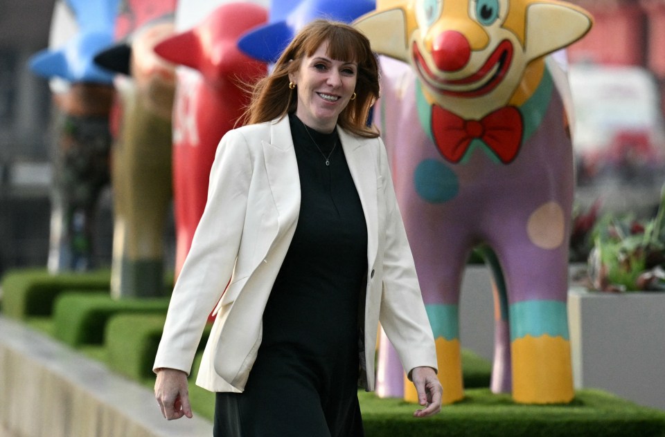 a woman in a white jacket stands in front of a clown statue