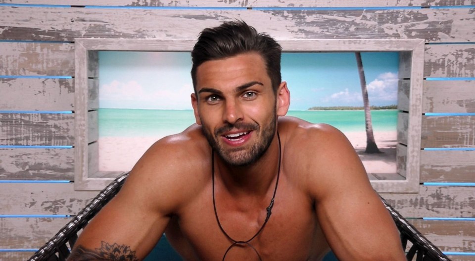 a shirtless man sits in front of a picture of a beach