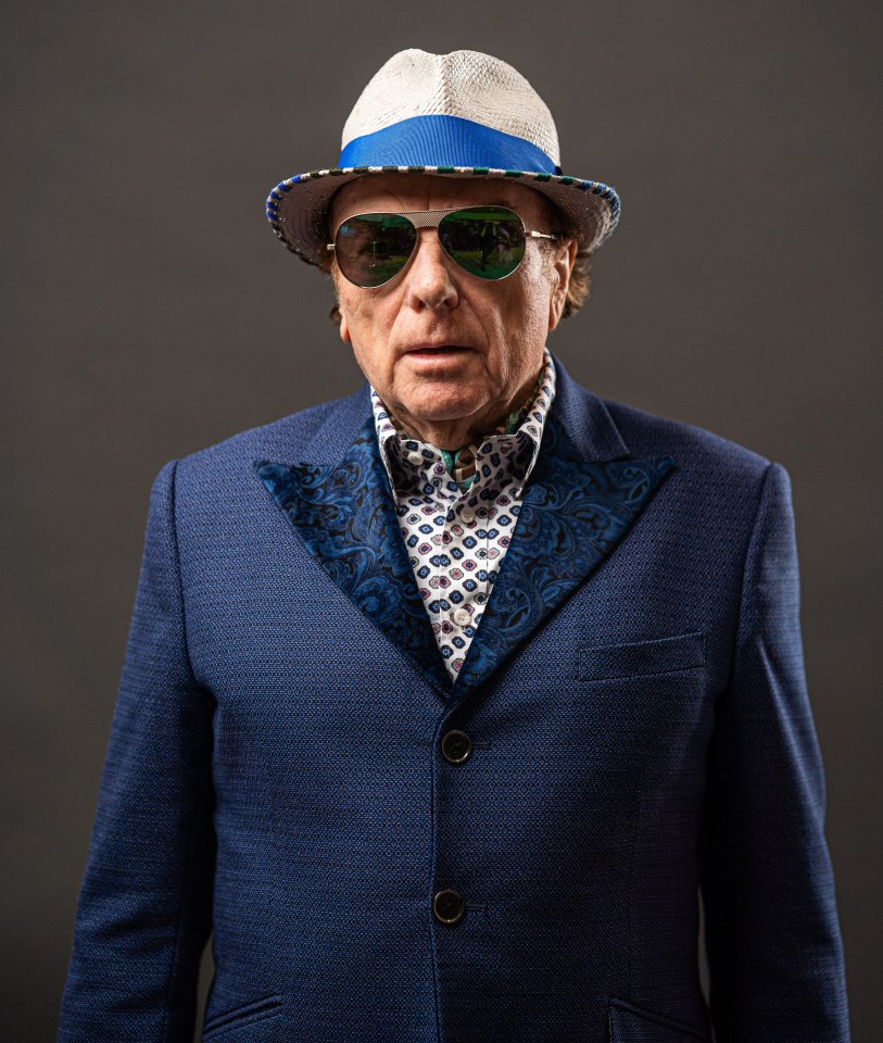 a man wearing a hat and sunglasses looks at the camera