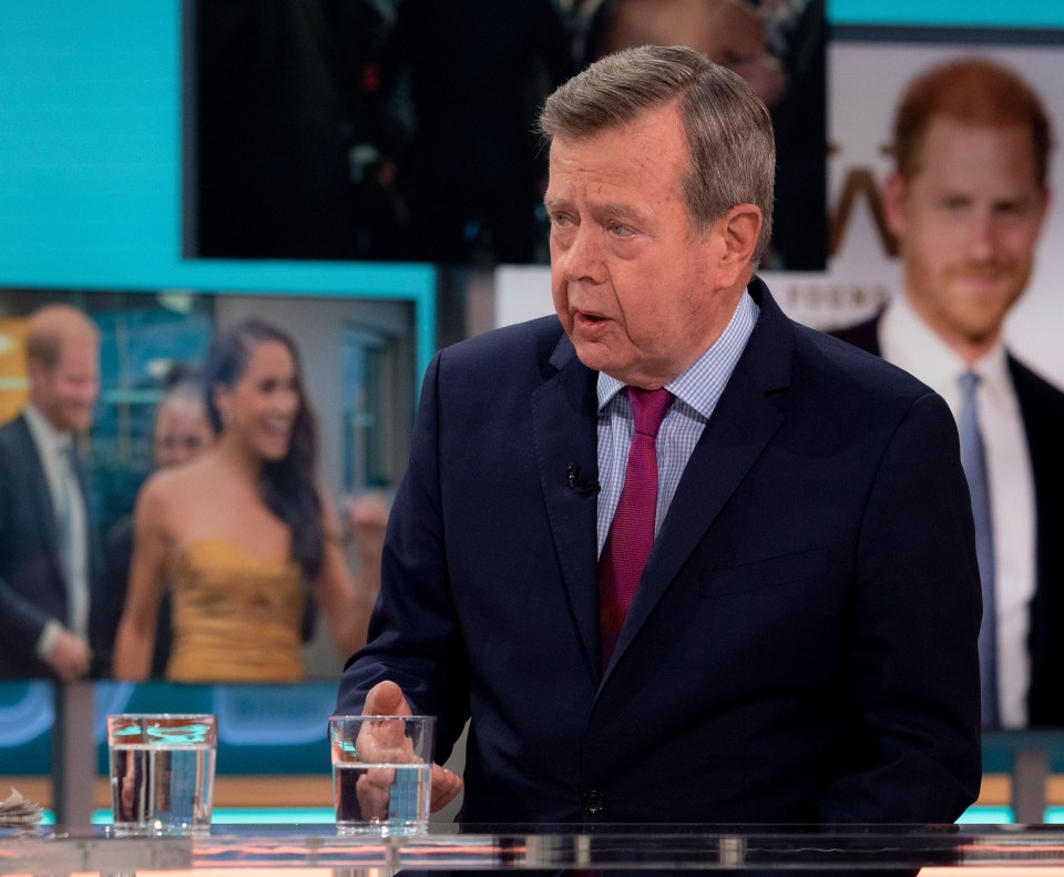 a man in a suit and tie is sitting at a table with a glass of water in front of him