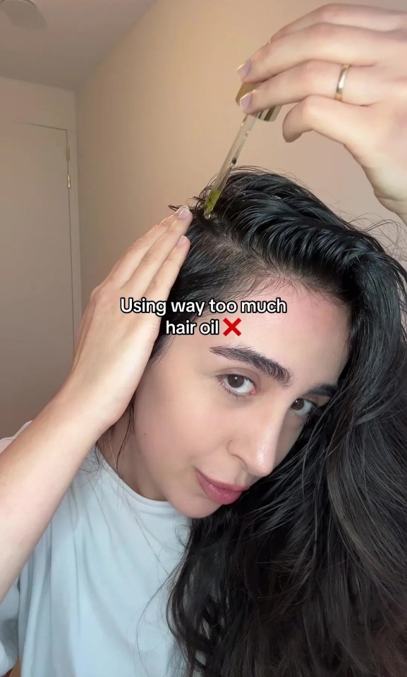 a woman applying oil to her hair with a caption that says using way too much hair oil x