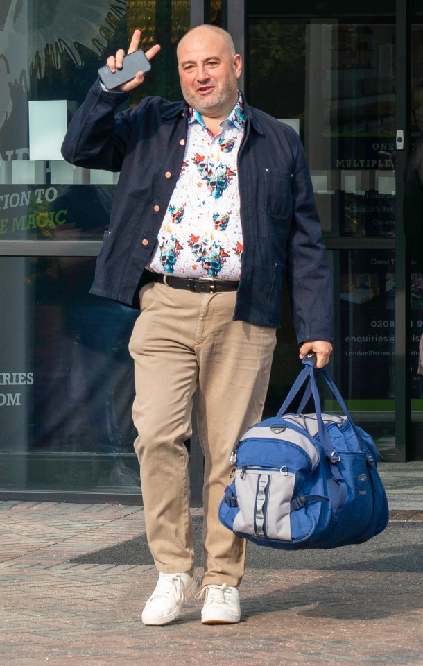 a man is carrying a blue bag and talking on a cell phone