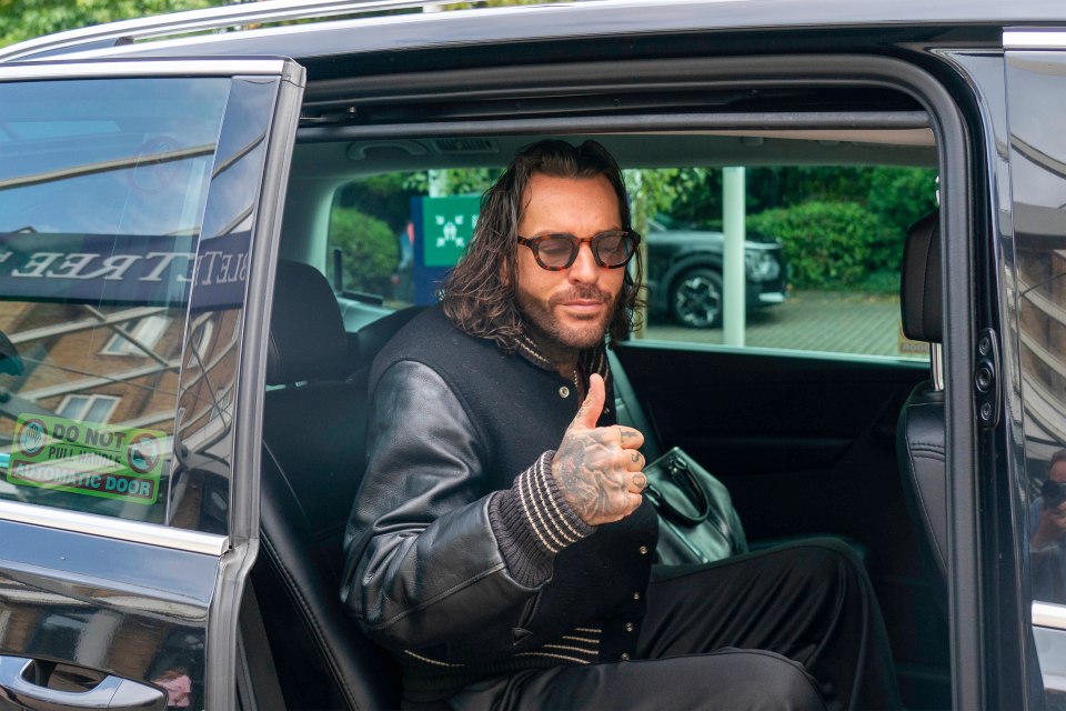 a man giving a thumbs up in the back seat of a car