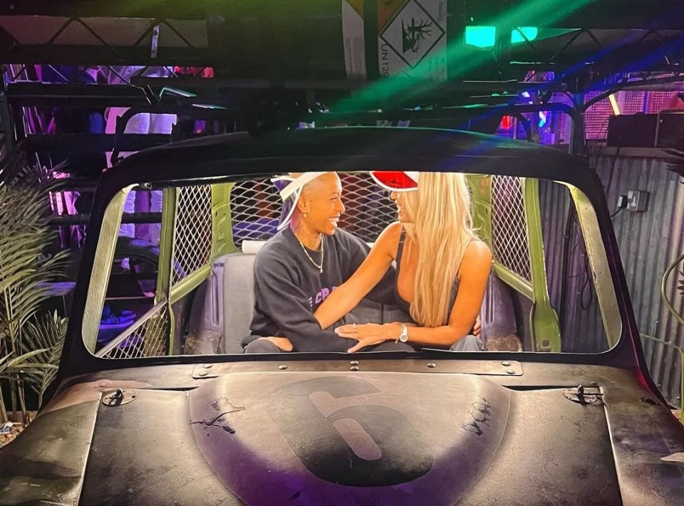 a man and a woman are sitting in a car under a sign that says #puttupurshot