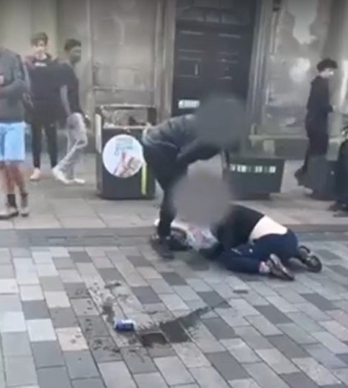 a man is kneeling on the ground while another man stands behind him .