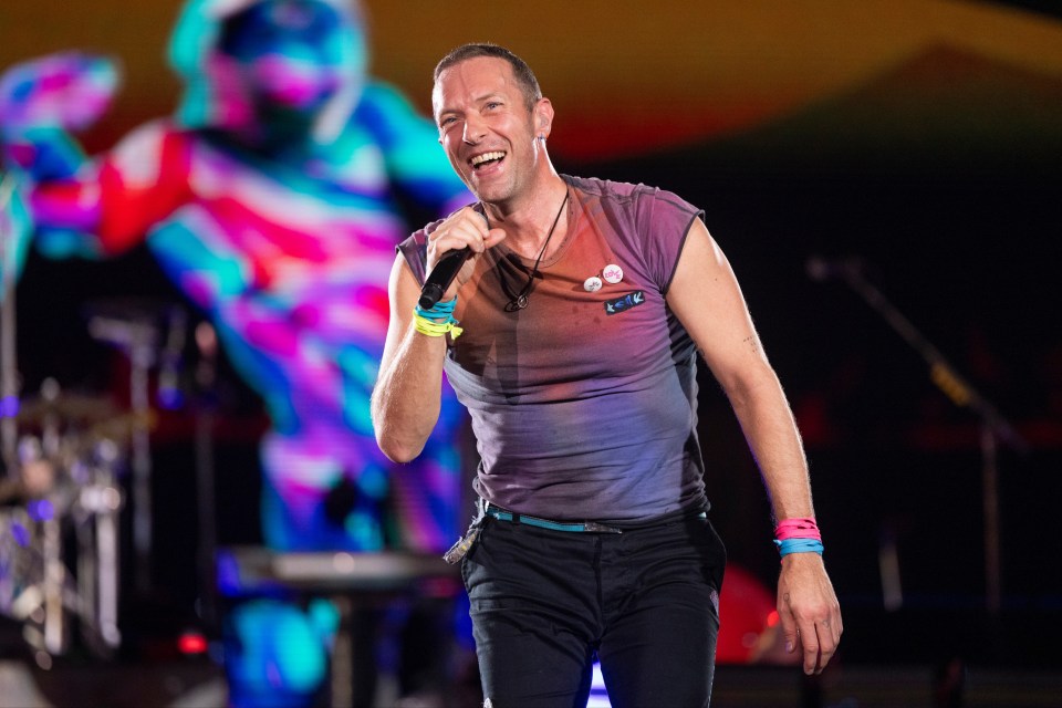 a man singing into a microphone with the word love on his shirt