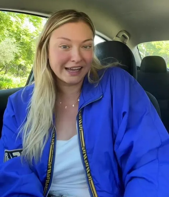 a woman in a blue jacket is sitting in a car