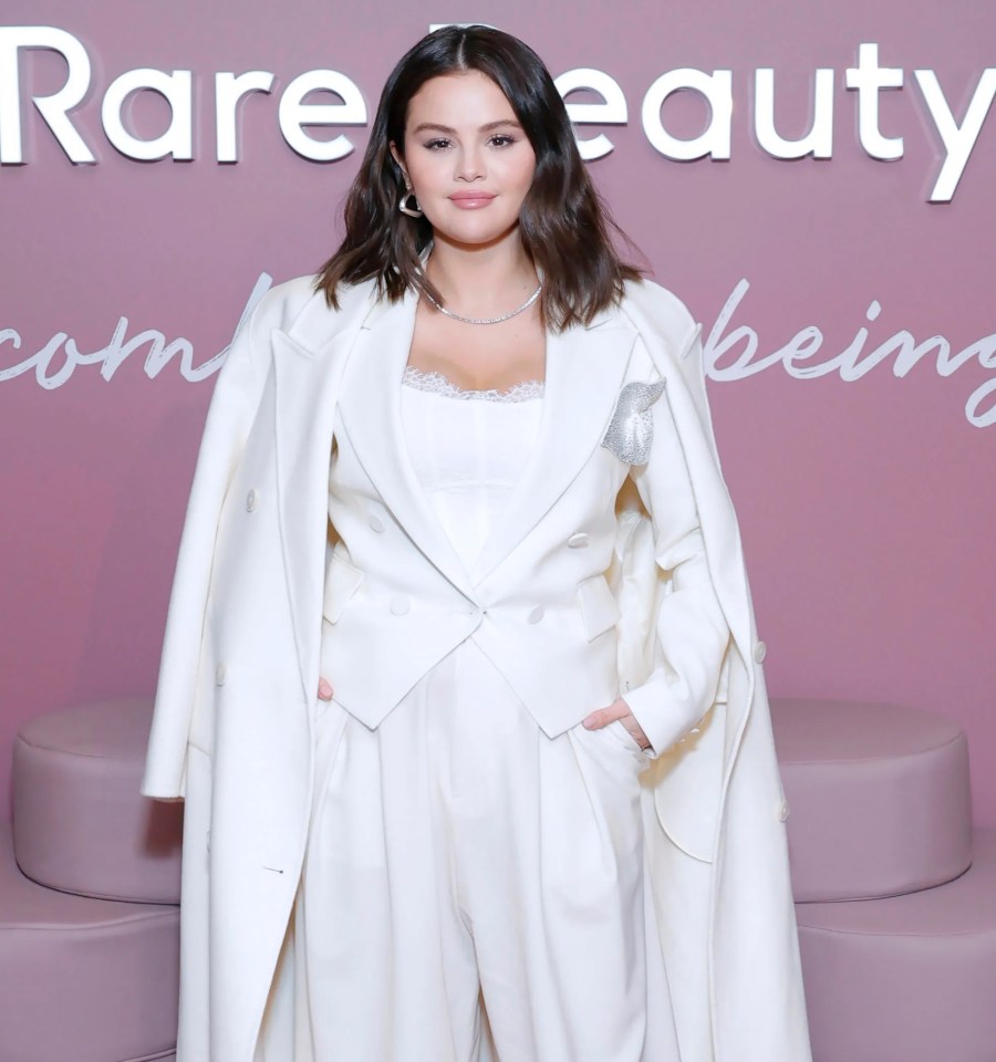 a woman stands in front of a sign that says rare beauty