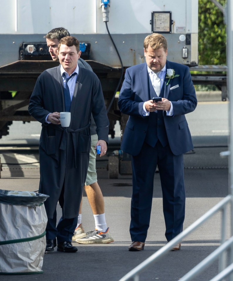 a man in a suit holds a cup of coffee and looks at his phone