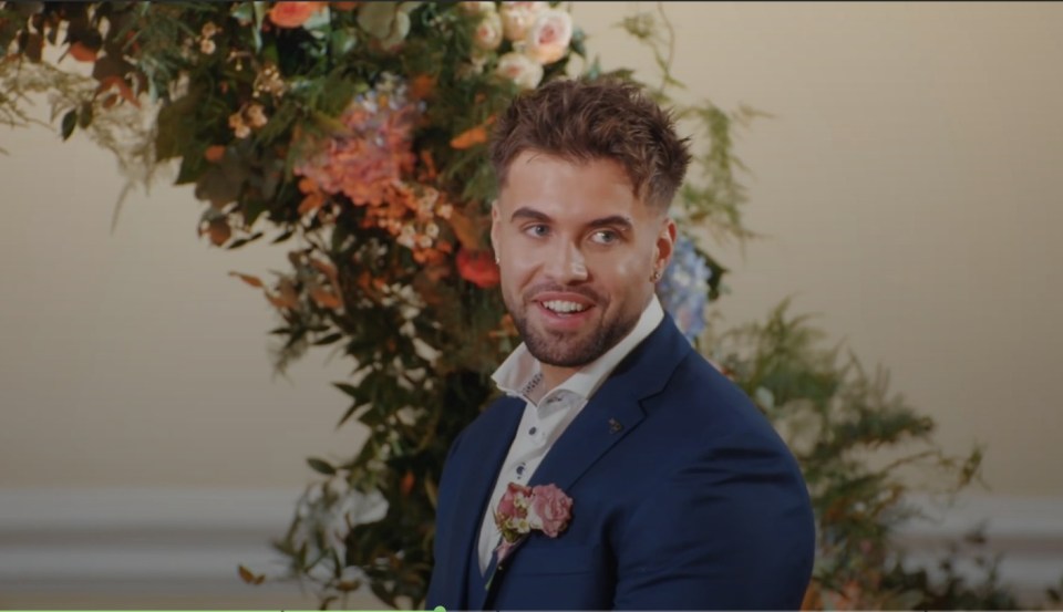 a man in a blue suit stands in front of a flower arrangement