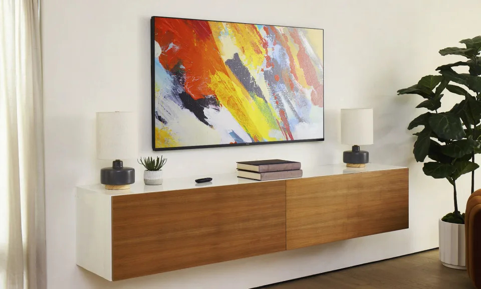 a colorful painting hangs above a wooden dresser