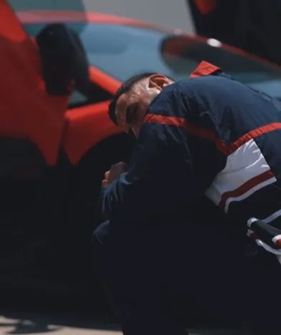 a man kneeling down in front of a red car