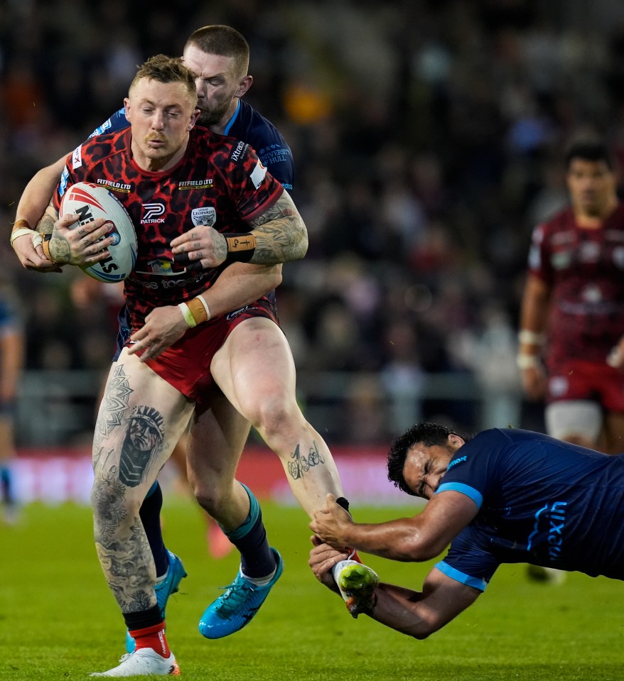 a rugby player with a tattoo on his leg runs with the ball