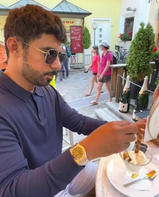 a man sits at a table with a bowl of ice cream and a bottle of champagne