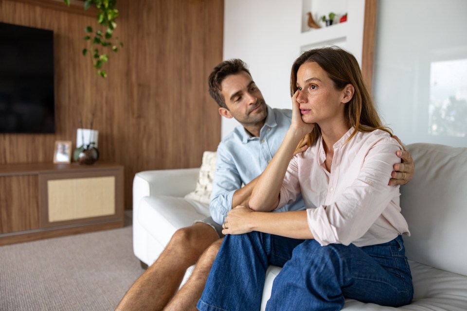 a man and woman sit on a couch looking at each other