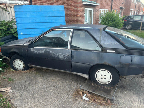 a black car is parked in front of a brick house