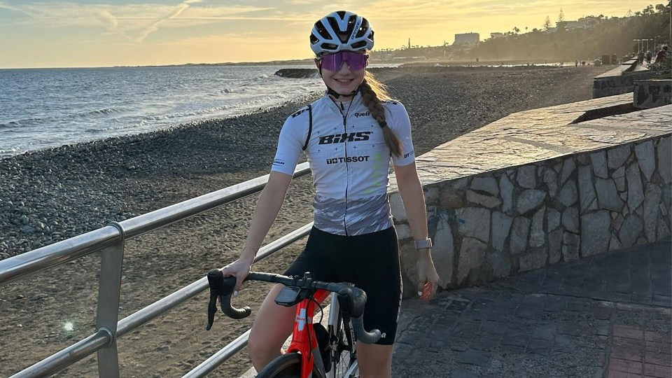 a woman wearing a behs jersey stands next to a bike