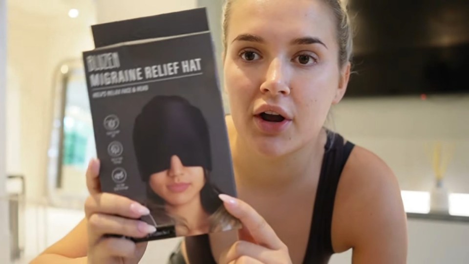 a woman is holding a box of a migraine relief hat