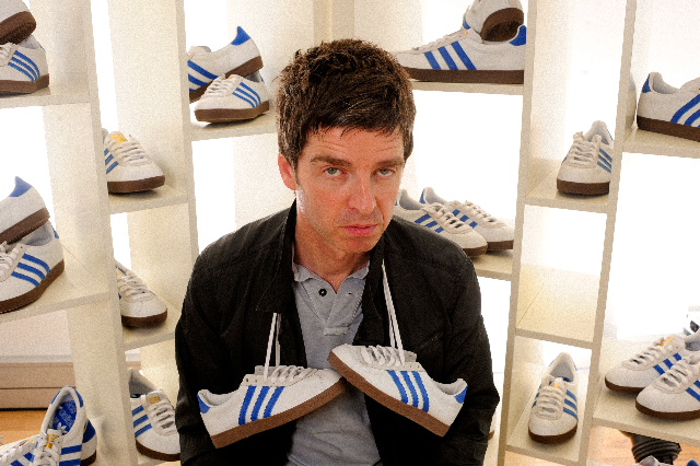 a man is holding a pair of blue and white adidas shoes