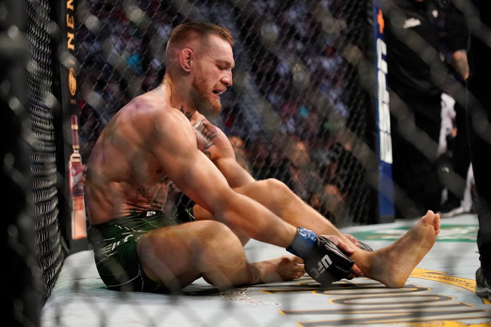 a fighter wearing a ufc glove sits on the ground