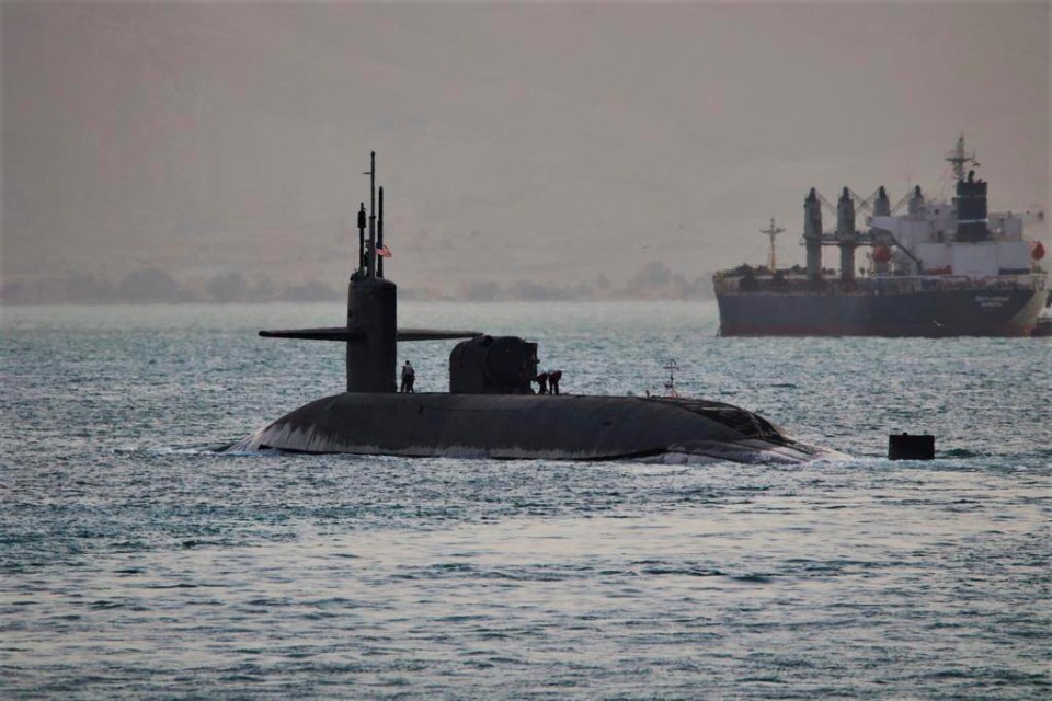 a submarine in the ocean with a large ship in the background