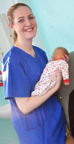 a nurse is holding a baby in her arms and smiling .