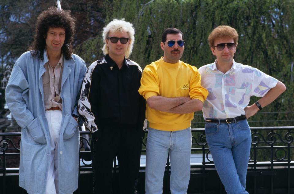 a man wearing a yellow shirt that says ' queen ' on it