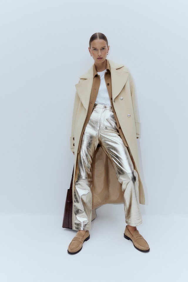 a woman wearing a trench coat and gold pants