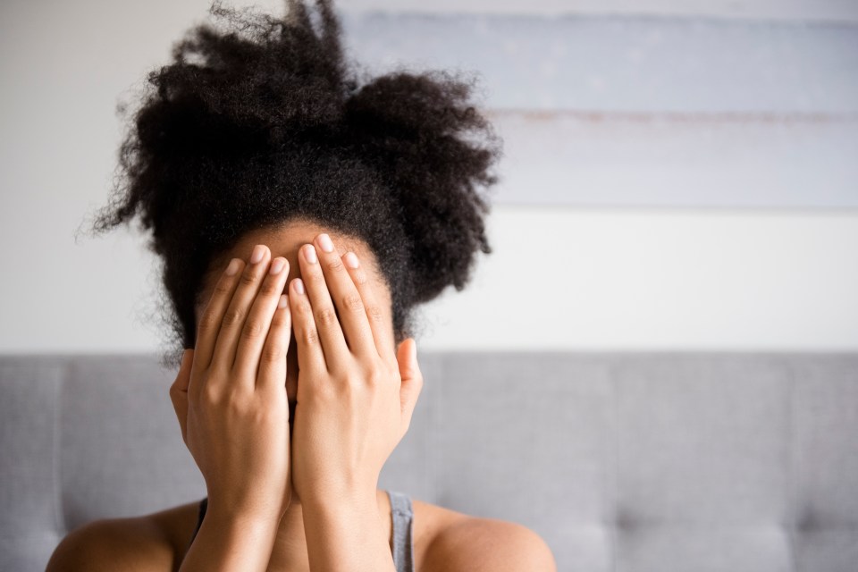 a woman is covering her face with her hands