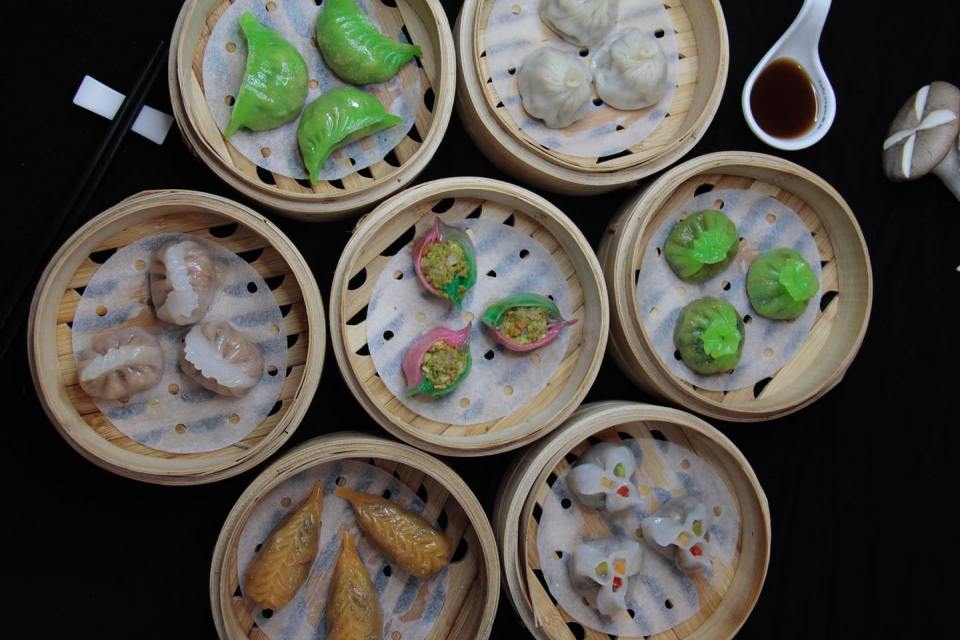 a variety of dim sum in bamboo baskets with chopsticks