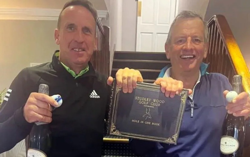 two men are standing next to each other holding a plaque and a bottle of champagne .