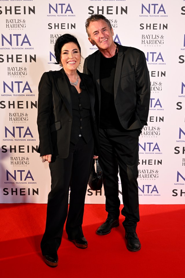 a man and woman are posing for a picture in front of a wall that says shein