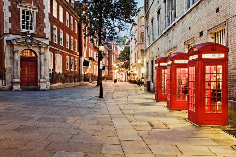 a row of red telephone booths on a sidewalk