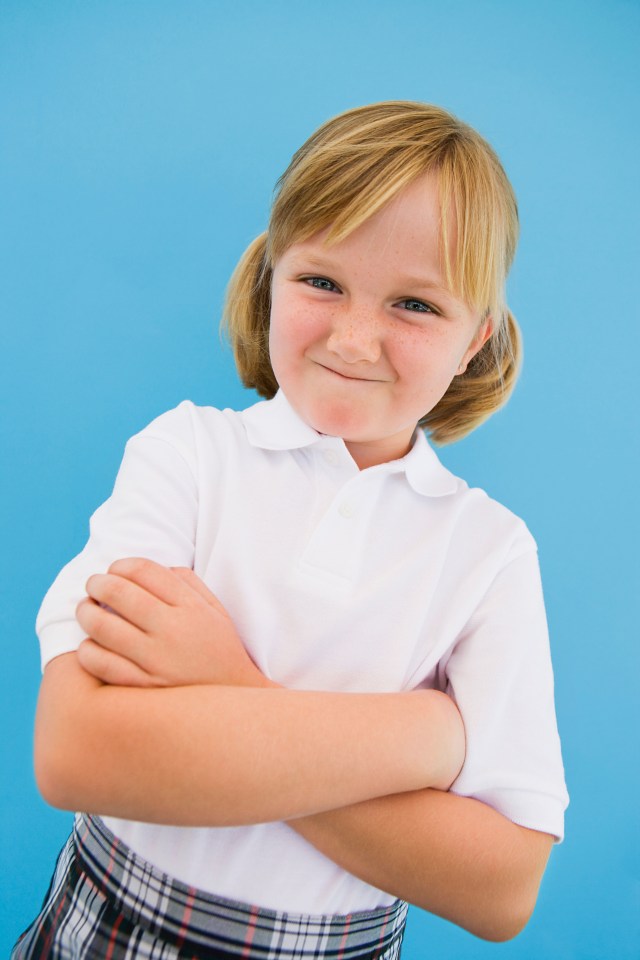 a young girl with her arms crossed looks at the camera