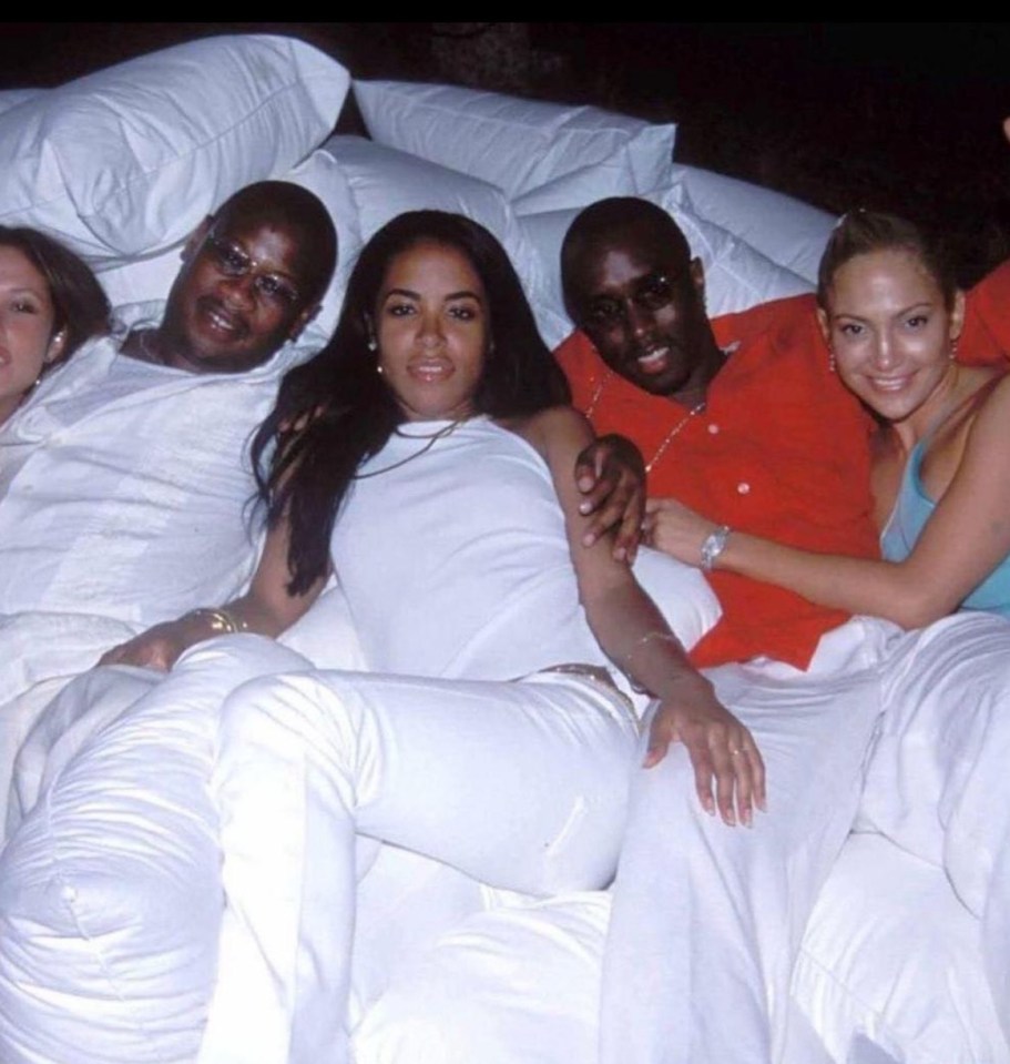 a group of people laying on a bed with white sheets