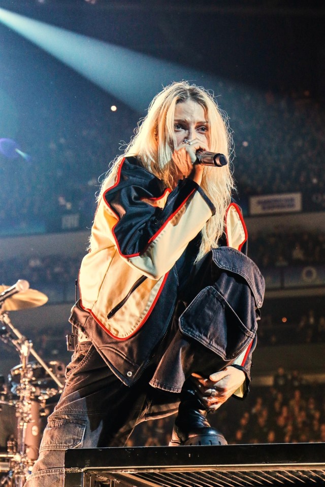 a woman singing into a microphone on a stage in front of a crowd